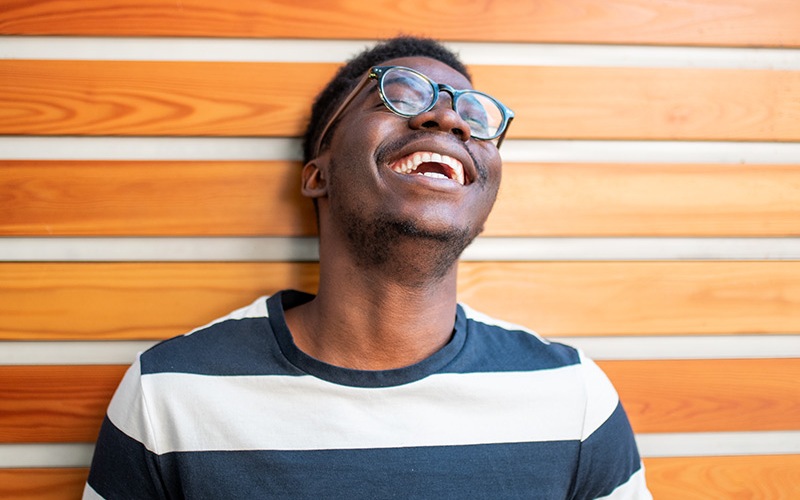 lifestyle image of a man laughing in front of a wooden wall