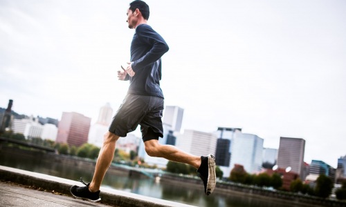 lifestyle image of a person running beside a river and city