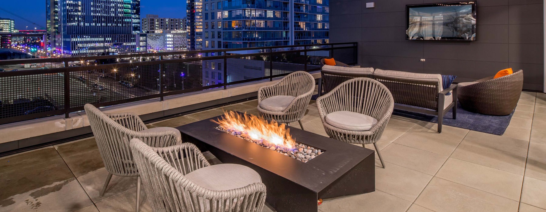 chairs around rooftop fire pit with city views